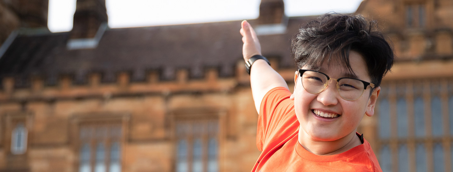 Student standing on campus gesturing