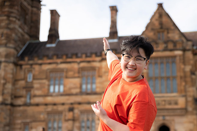 Student standing on campus gesturing