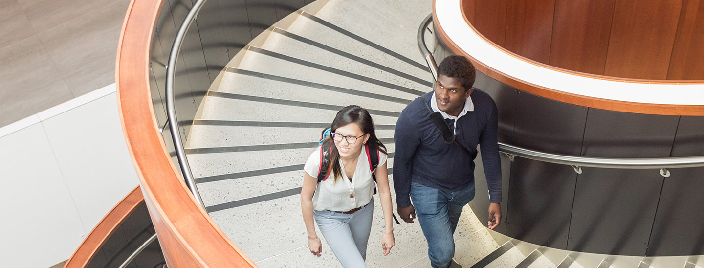 Students walking inside campus spiral staircase