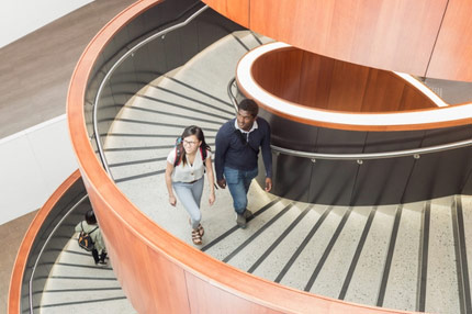 Students walking inside campus spiral staircase